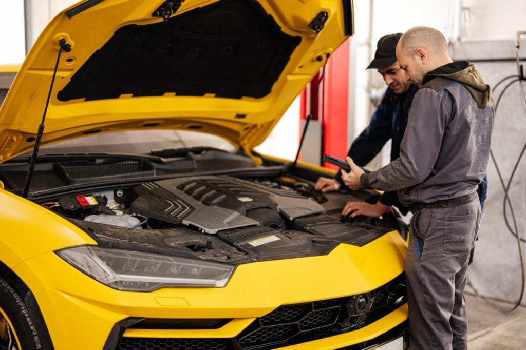 two mechanics stand with tablet against open hood of yellow sport car suv - Jerry Zister, auto shop for car repair and maintenance in Kitchener, Ontario