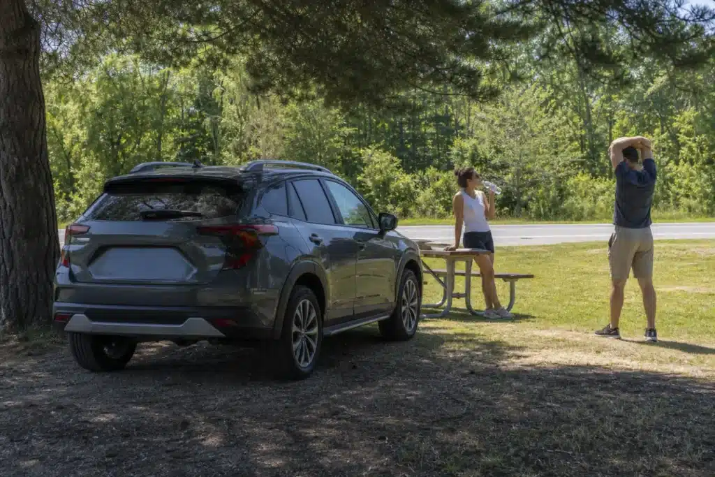 Couple taking a shaded break beside their SUV during an Ontario summer road trip
